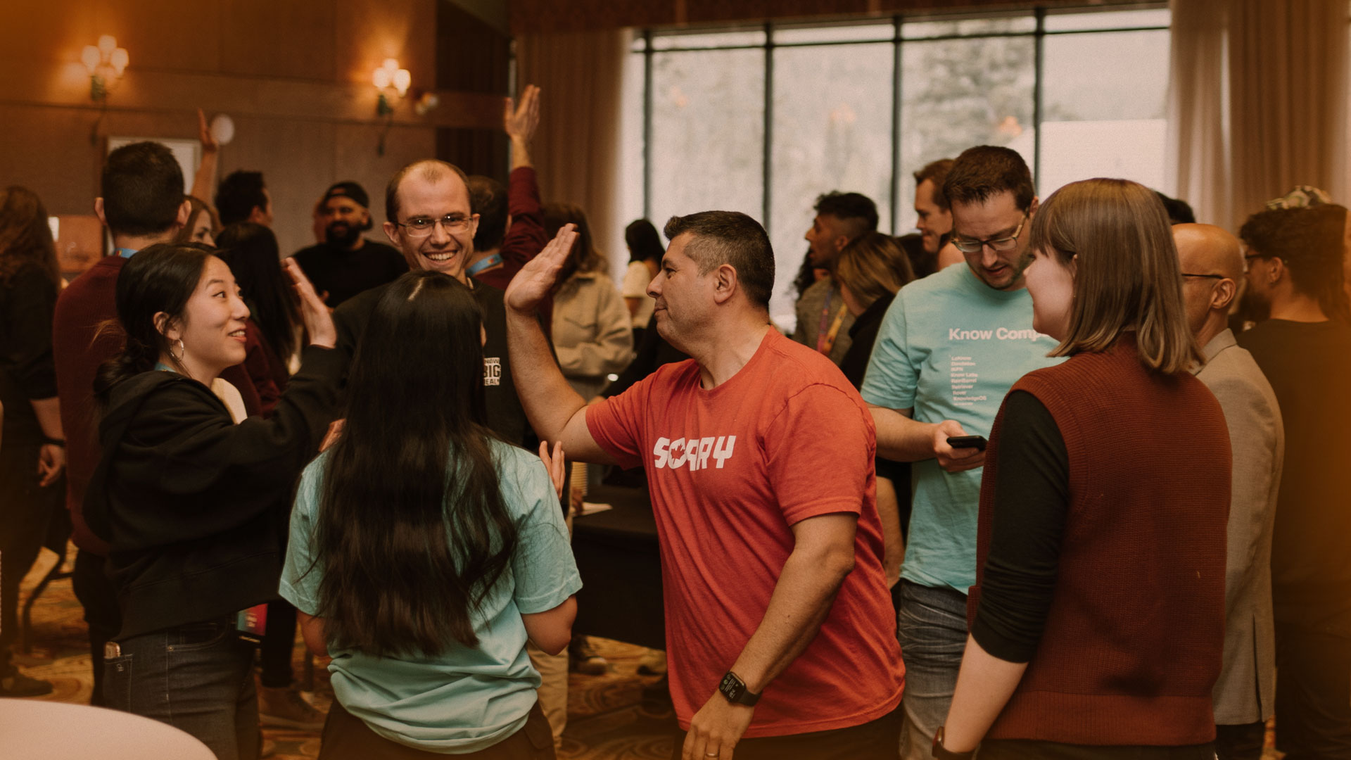 A photo of Know Company employees high-fiving and having a good time together at a company event.